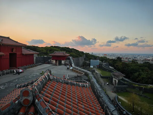 Widok na zamek Shuri (首里城) w mieście Naha na Okinawie o zachodzie słońca. Charakterystyczne czerwone budynki i kamienne mury to symbol dawnego Królestwa Riukiu.